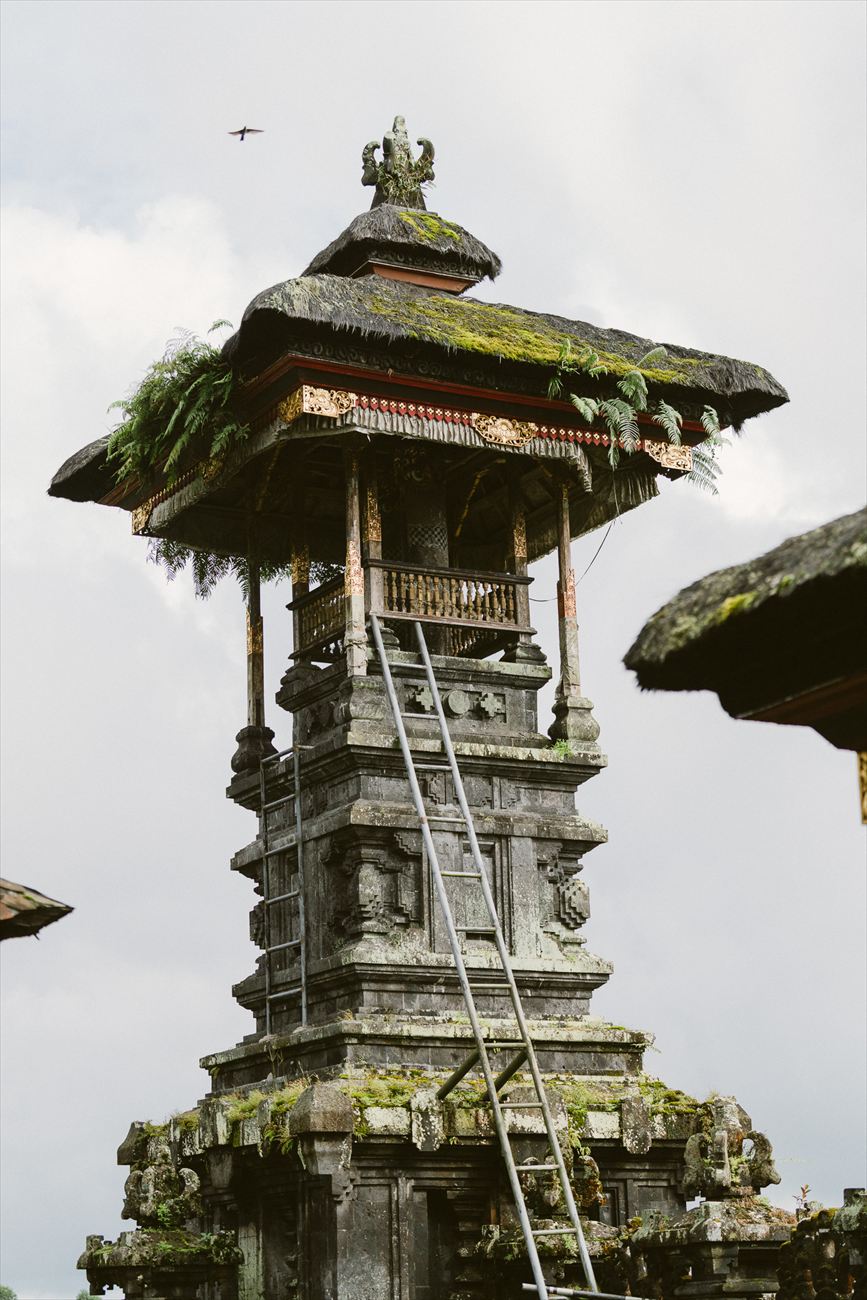 A mossy stone shrine tower against a pale sky