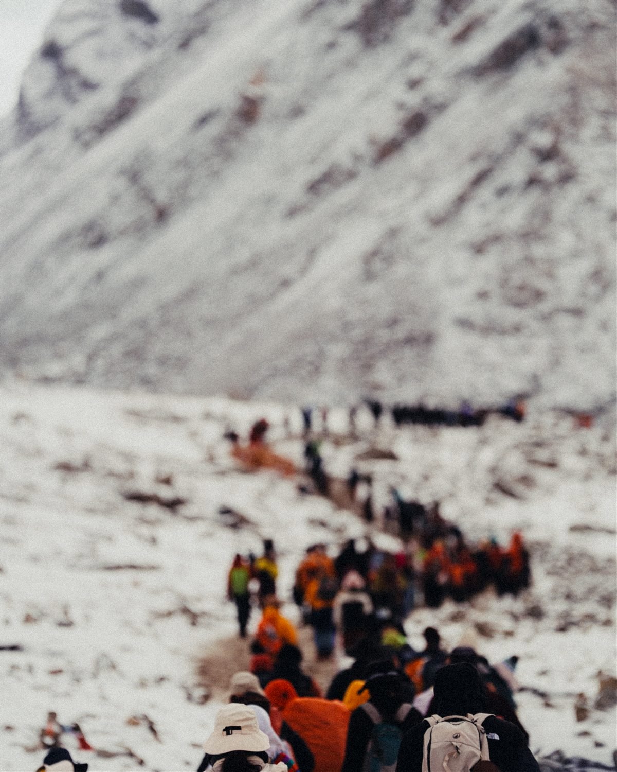 A line of people walking together up a snowy mountain pass