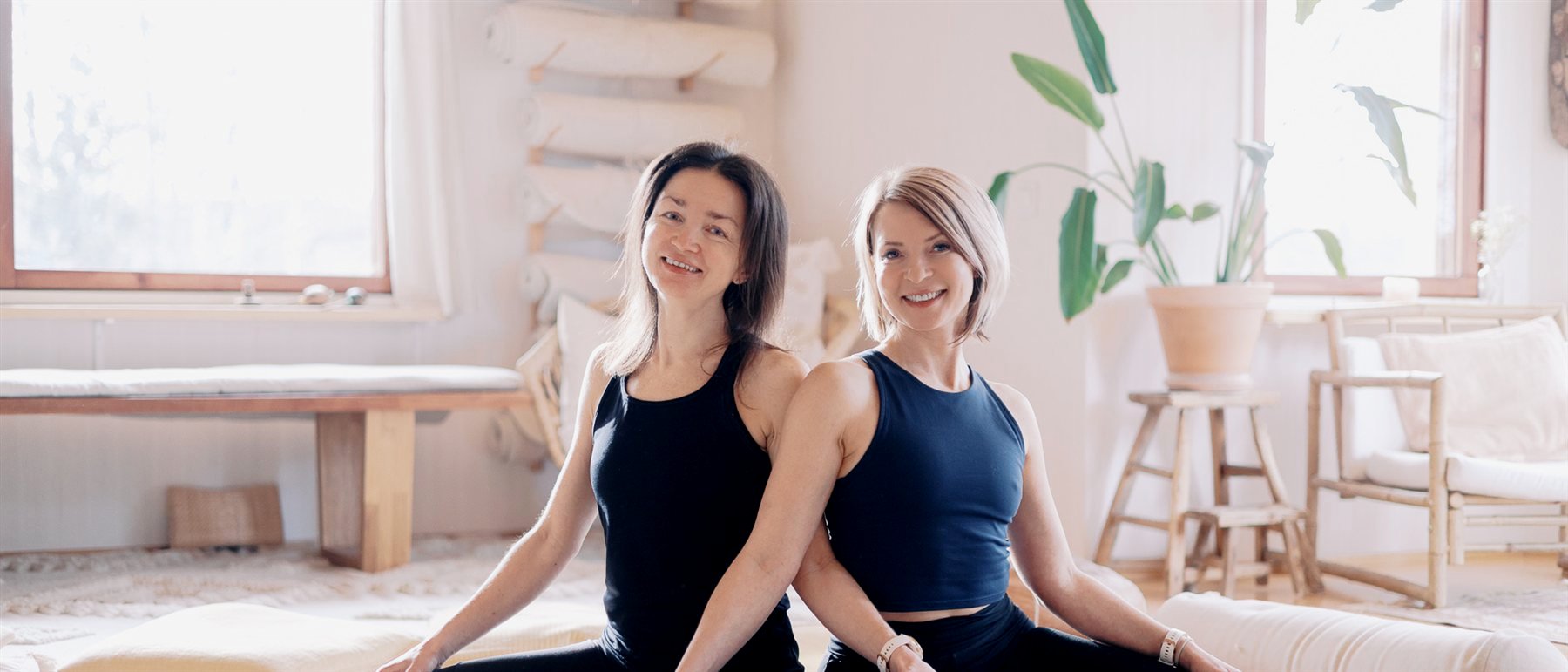 Two facilitators sitting back to back in a bright studio