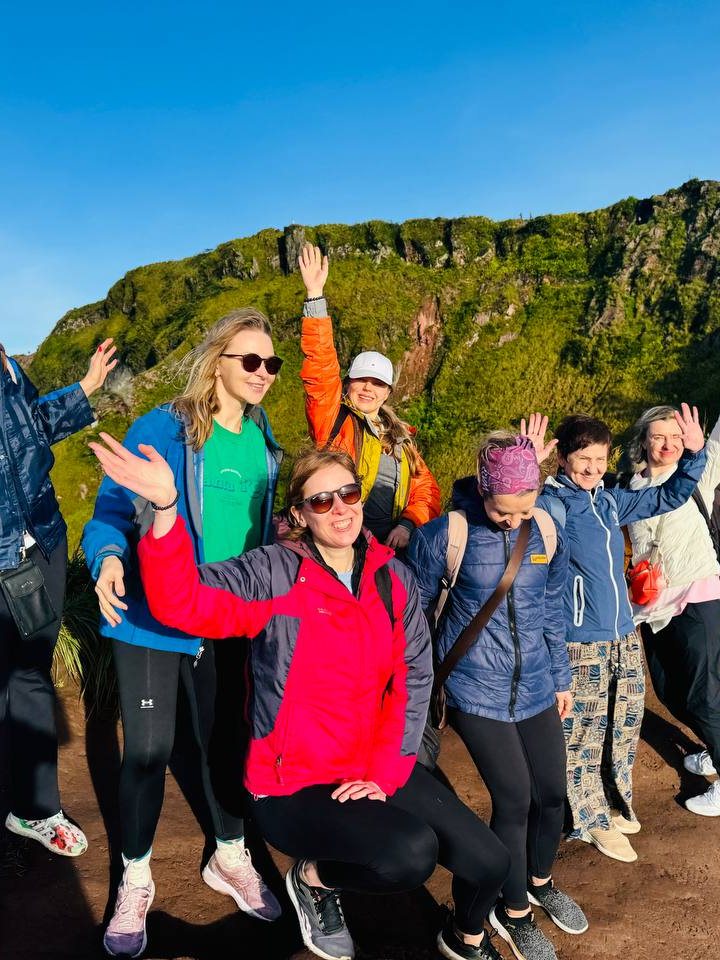 A Curious Souls group together on a volcano rim in Bali, arms raised