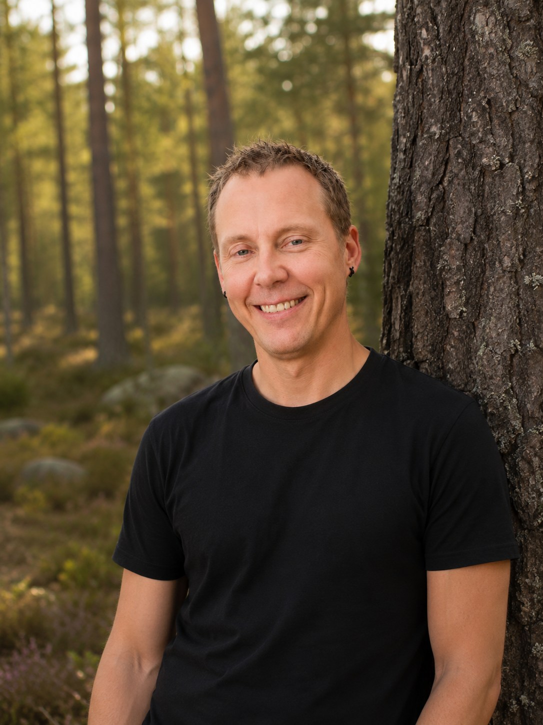 Daniil beside a pine trunk in a Finnish forest