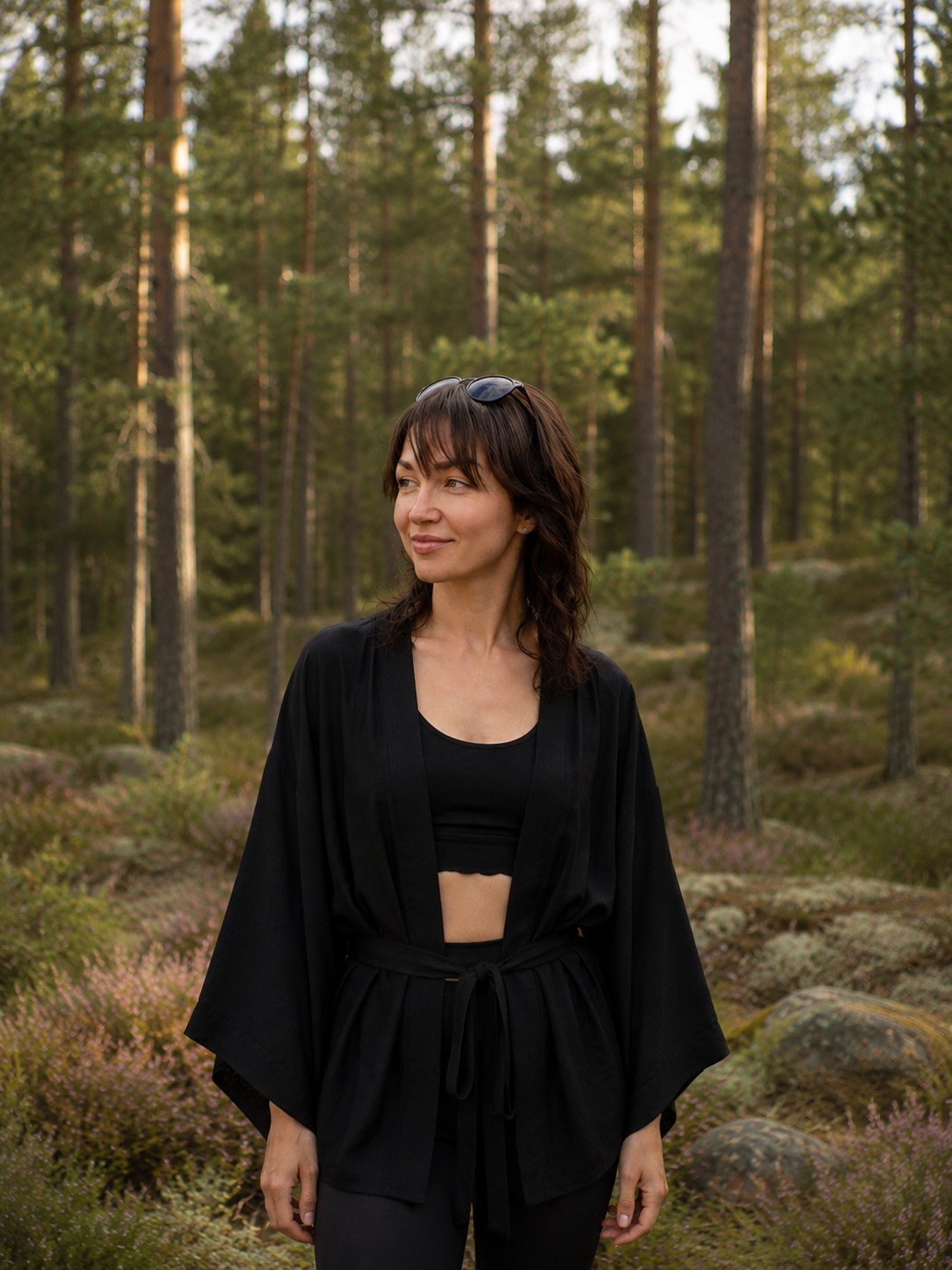 Evgenia standing among pines and heather in a Finnish forest