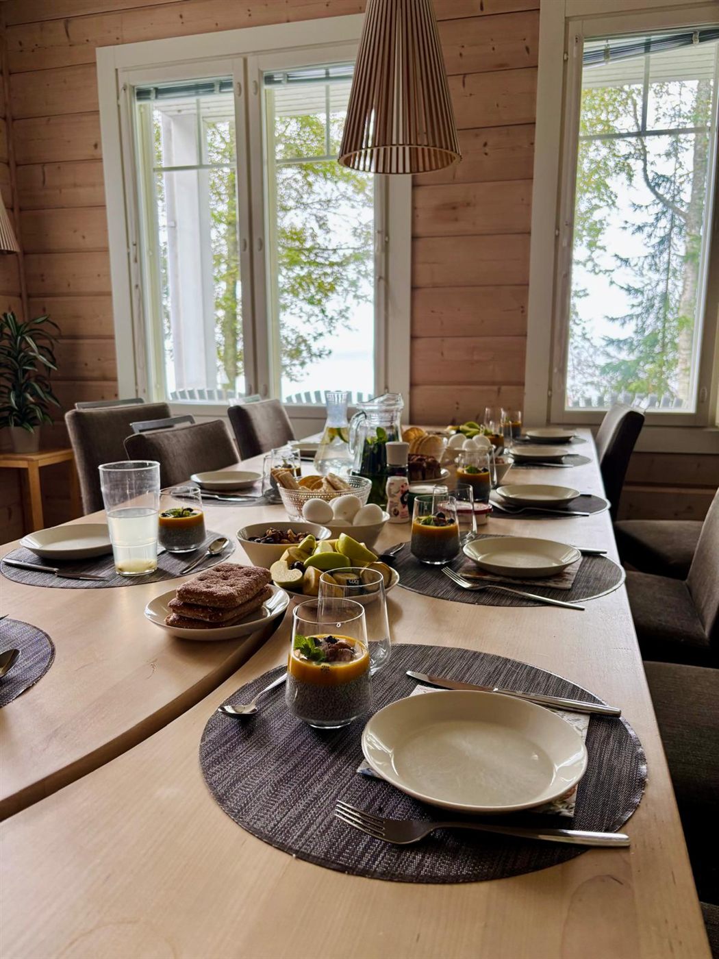 A long wooden table laid for a shared meal in a timber-lined villa
