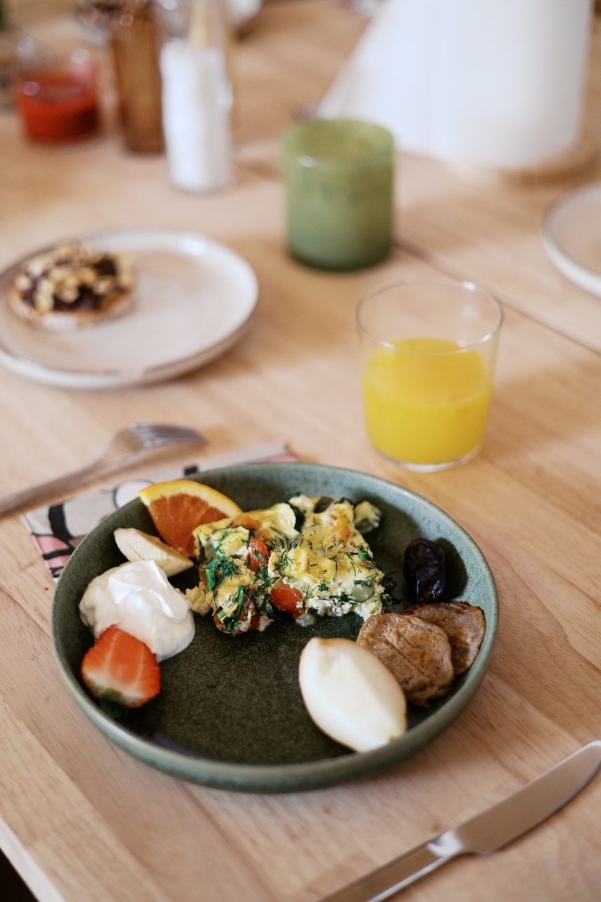 A breakfast plate on a warm wooden table, juice and candles alongside