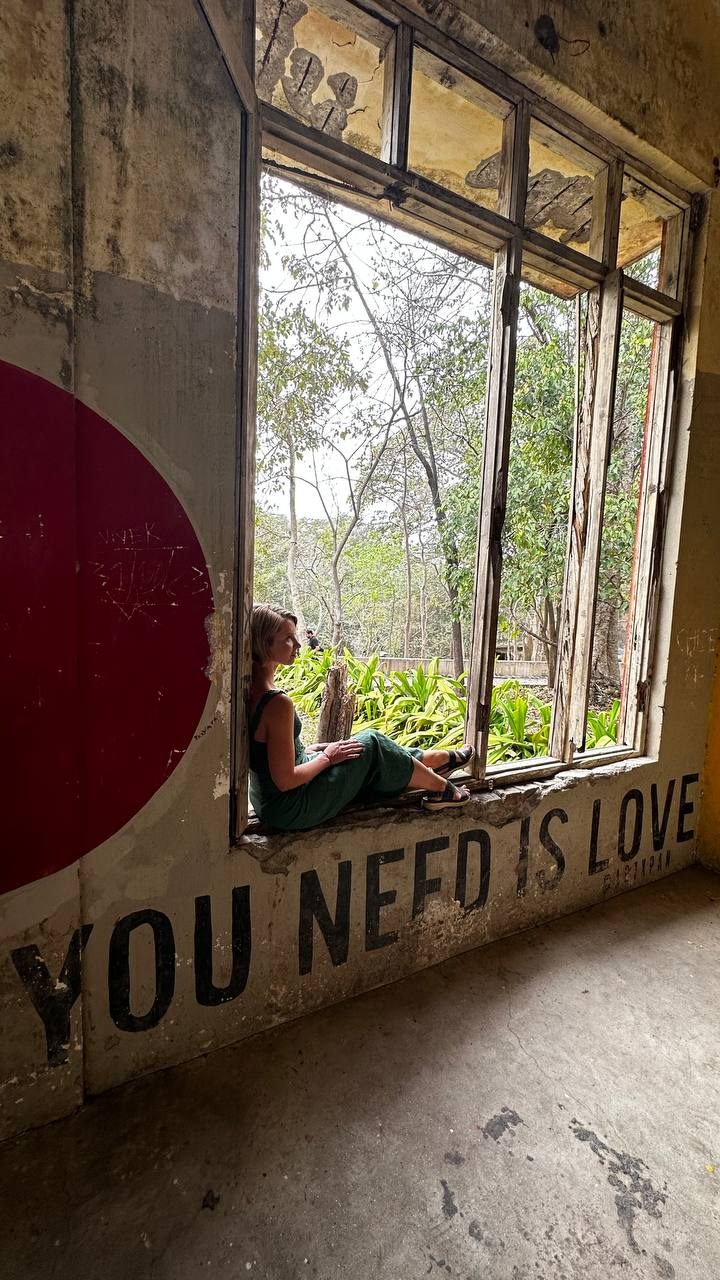Someone sitting in a wide window frame beside a painted wall