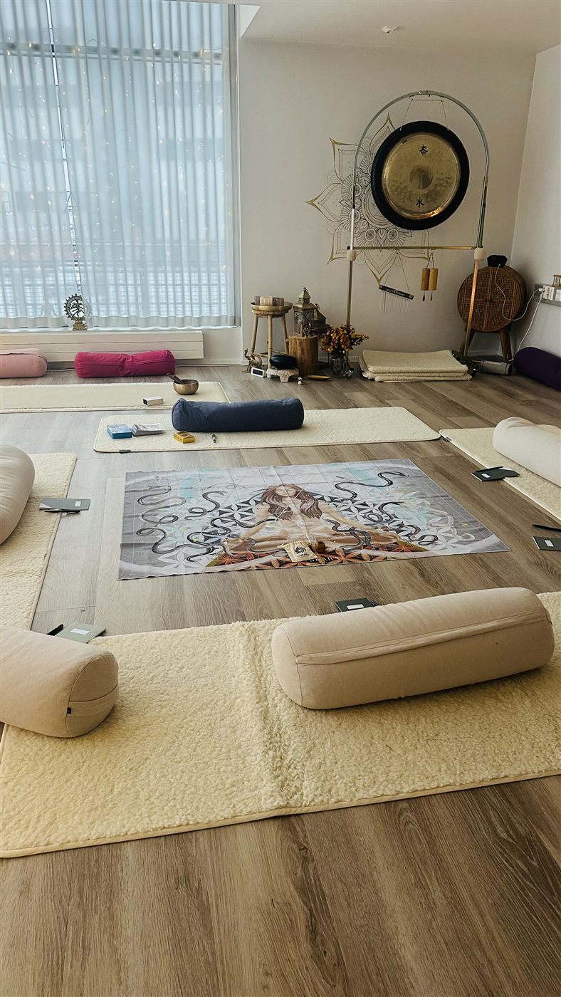 A quiet room set with mats, bolsters and blankets, a gong standing at the far wall