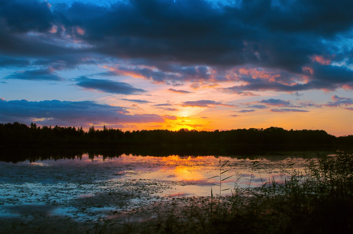 Sunset over a still Finnish lake, cloud and colour mirrored in the water