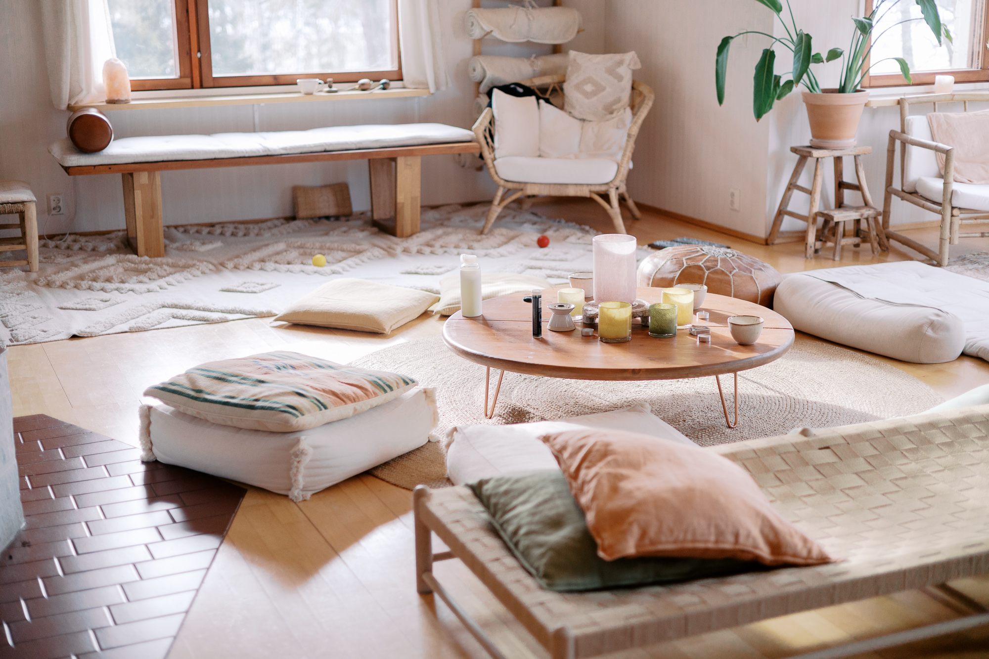 A warm room laid out with floor cushions and candles before a gathering