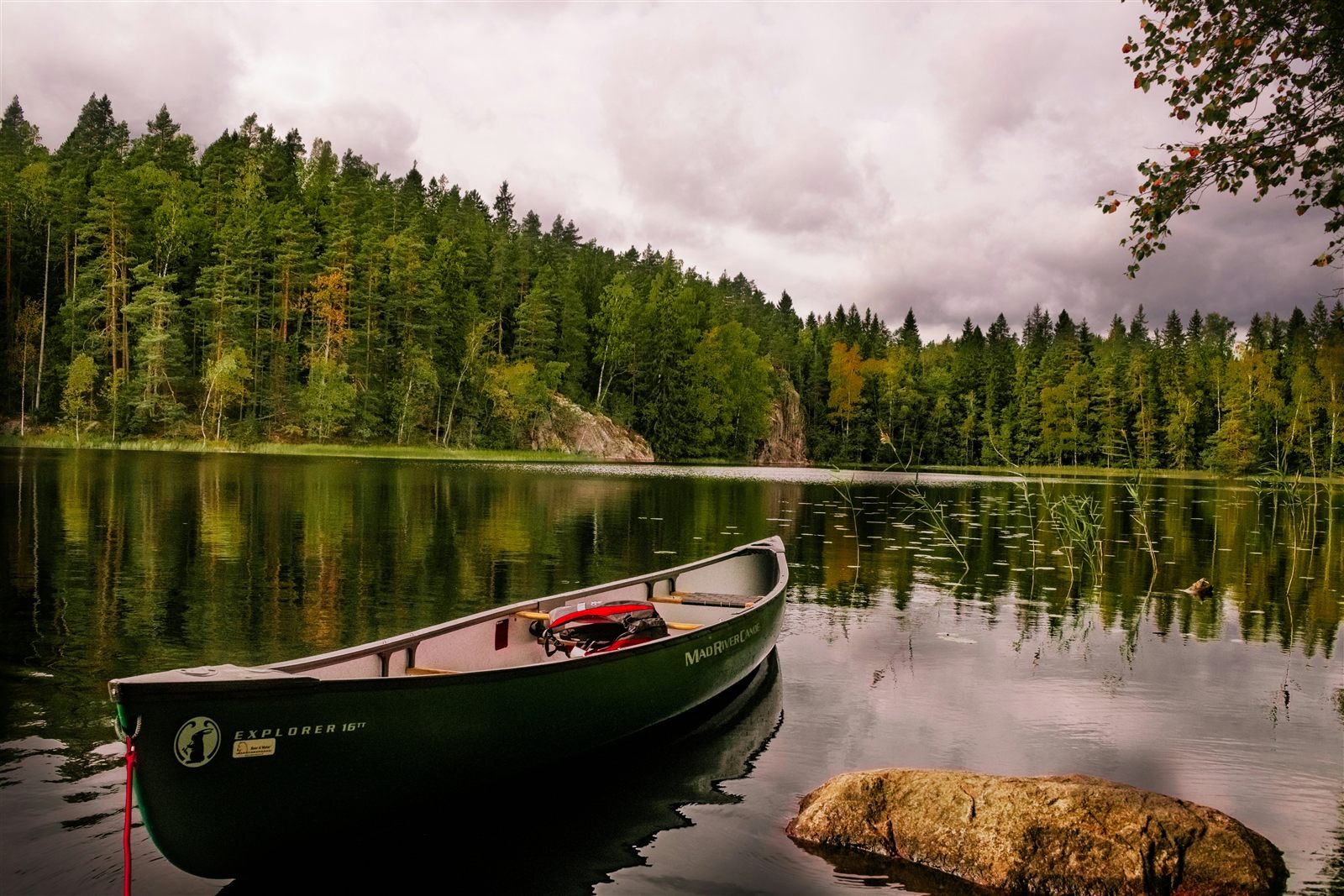A canoe moored on a still lake edged with Finnish forest