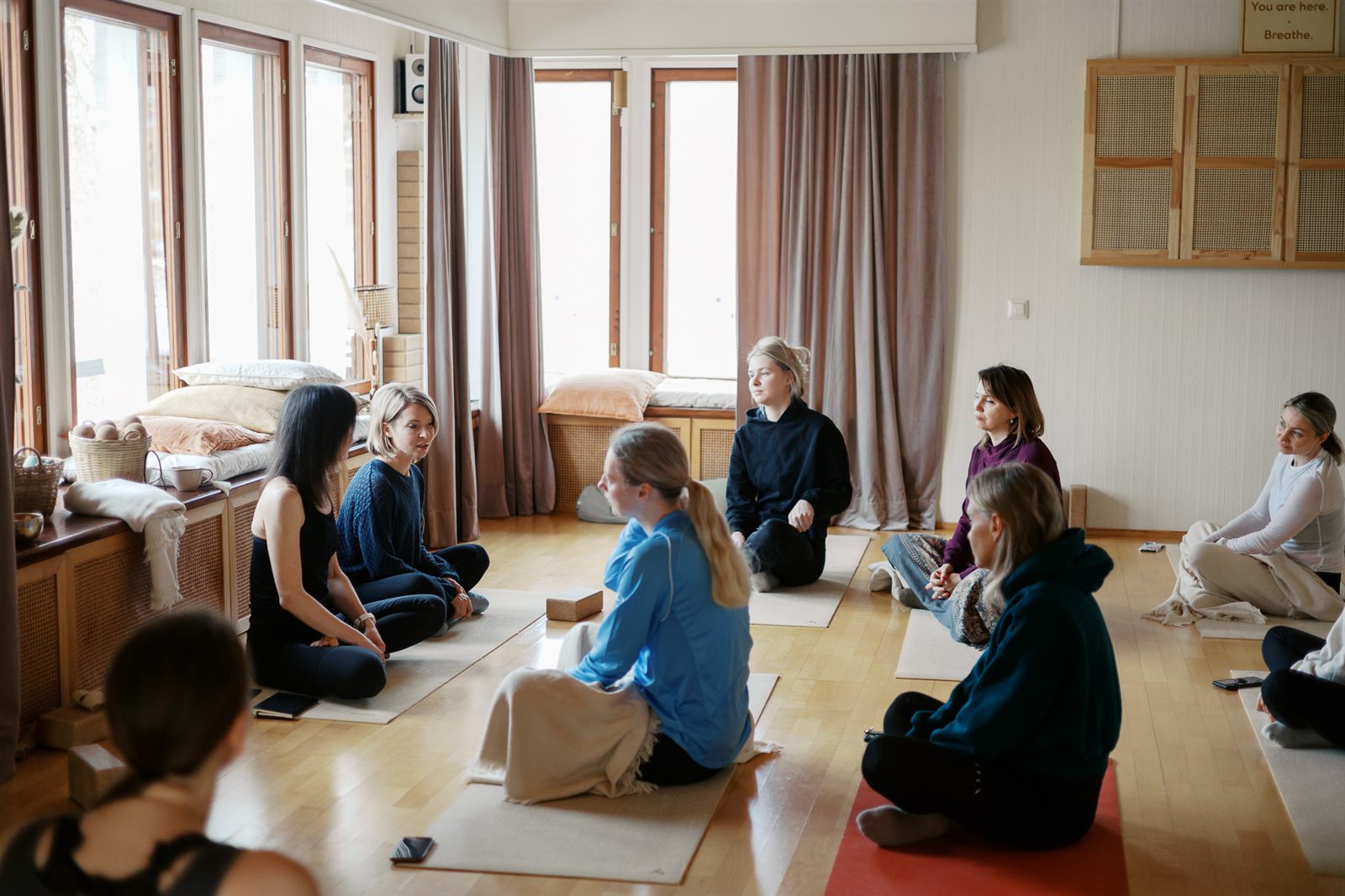 A circle of people sitting together in a bright room at Villa Saga