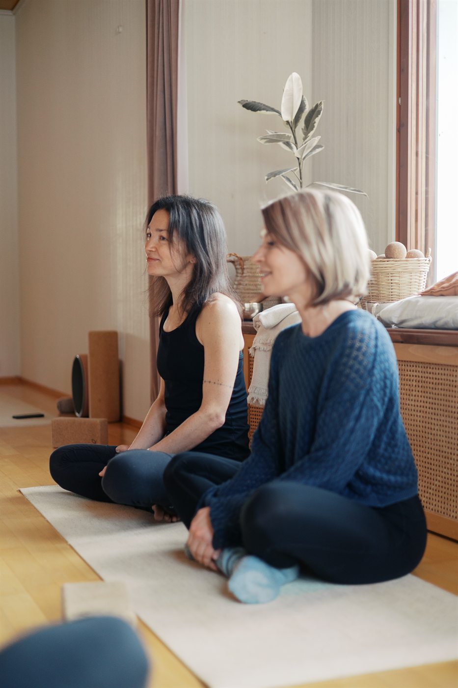Two people sitting on the floor of a sunlit room, deep in conversation