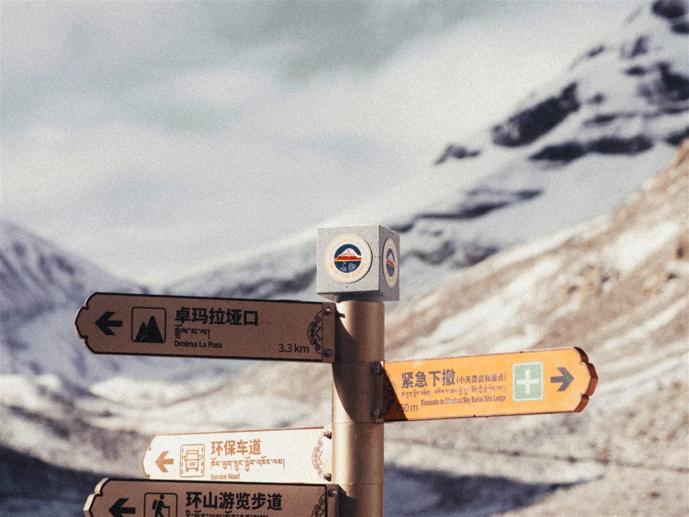 A trail signpost pointing several ways on a snowy mountain pass