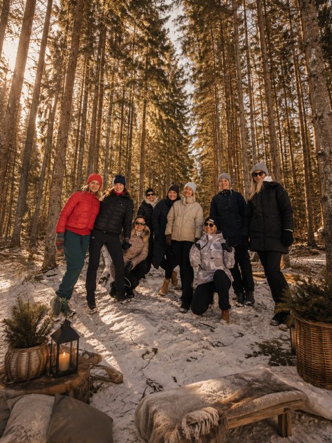 The group together in a sunlit snowy pine forest